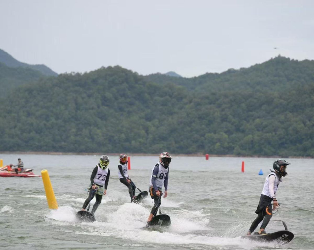 Zawody na elektrycznych jetboardach — czterech zawodników ściga się na deskach elektrycznych na jeziorze